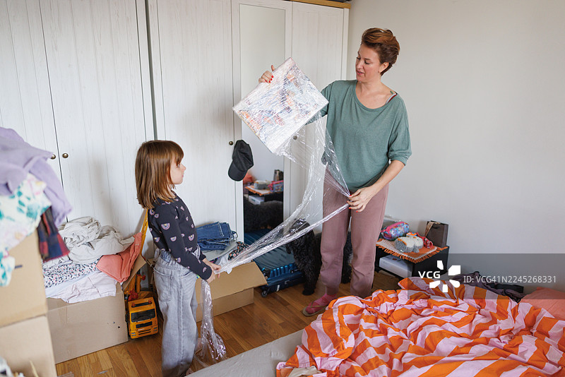 女人和女儿在卧室打包，用锡纸包裹照片，搬家图片素材