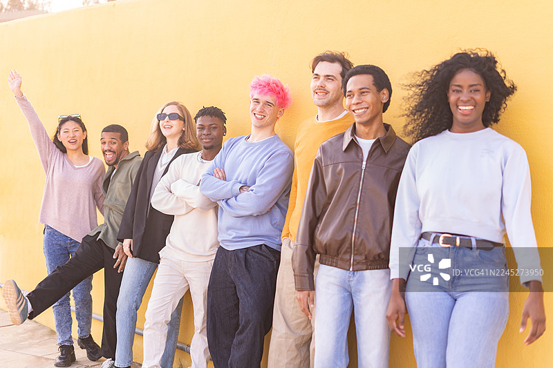 快乐的多元化年轻人在鲜艳的黄色墙壁前合影图片素材