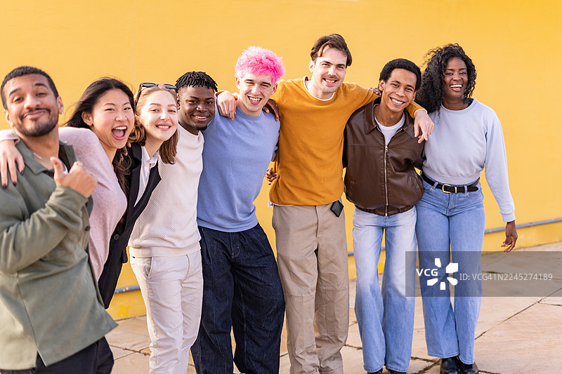 一群快乐的多民族年轻人在鲜艳的黄色墙壁前合影图片素材