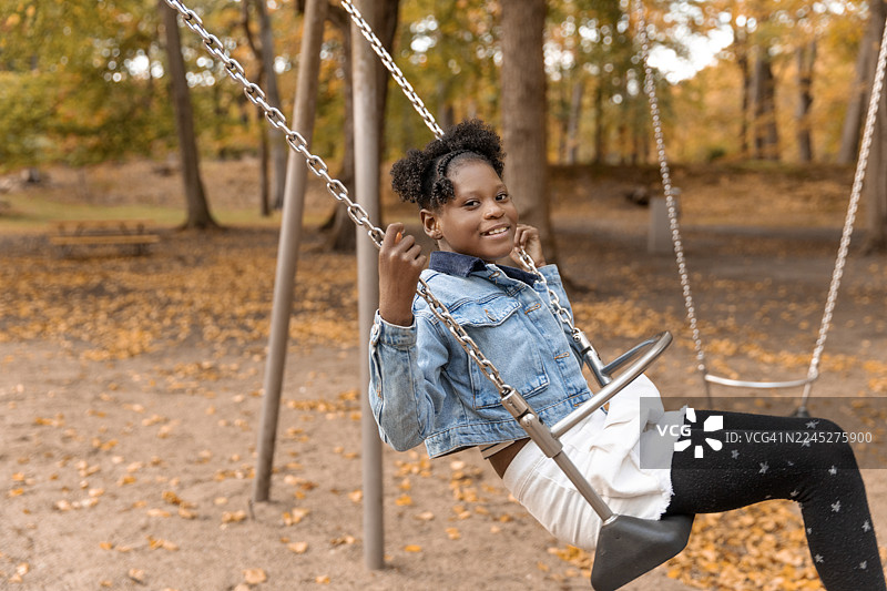 一个漂亮的黑人女孩在公园的秋日散步中玩耍图片素材
