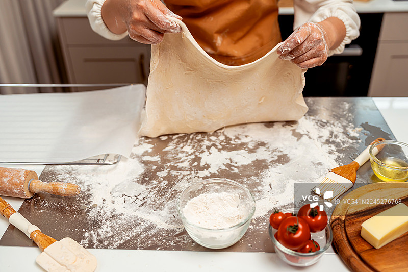 亚洲女性在家里的厨房为节日家庭聚会制作自制披萨。图片素材