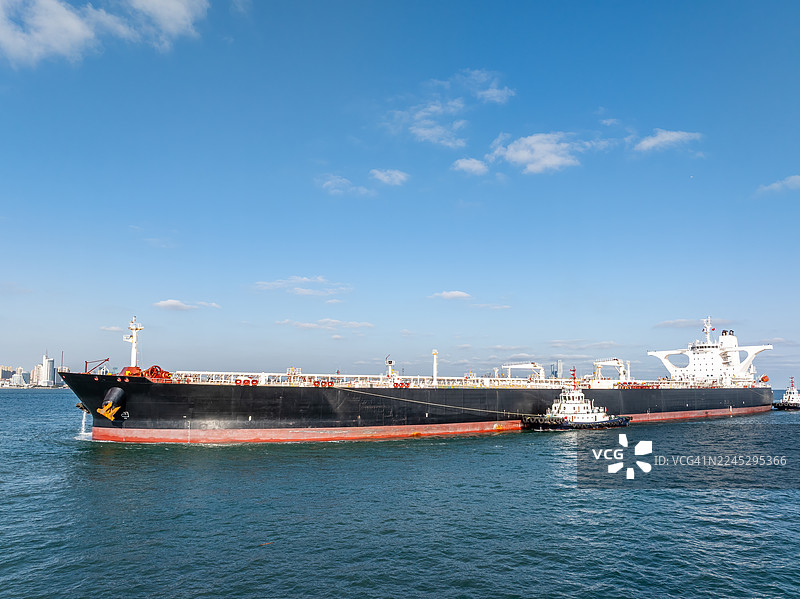 无人机视角拍摄的油轮在青岛城市天际线前海上航行图片素材