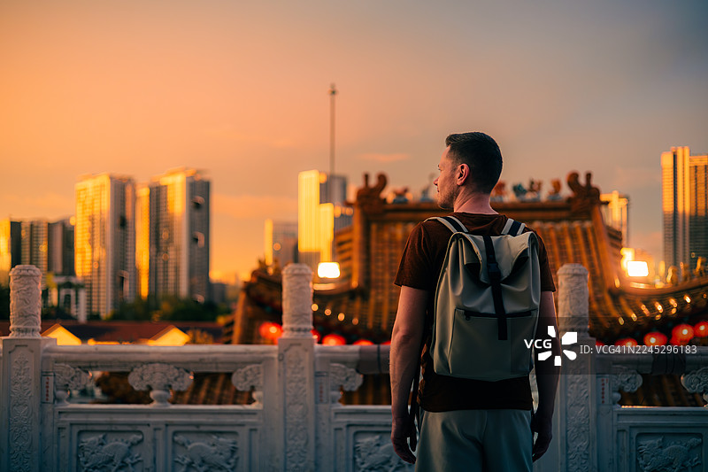 日落时分，背着背包的游客从灯火辉煌的慈航寺后方走过图片素材