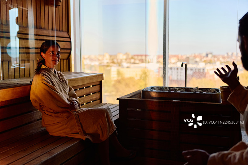 情侣在桑拿房放松，享受健康疗养，并欣赏城市景观图片素材