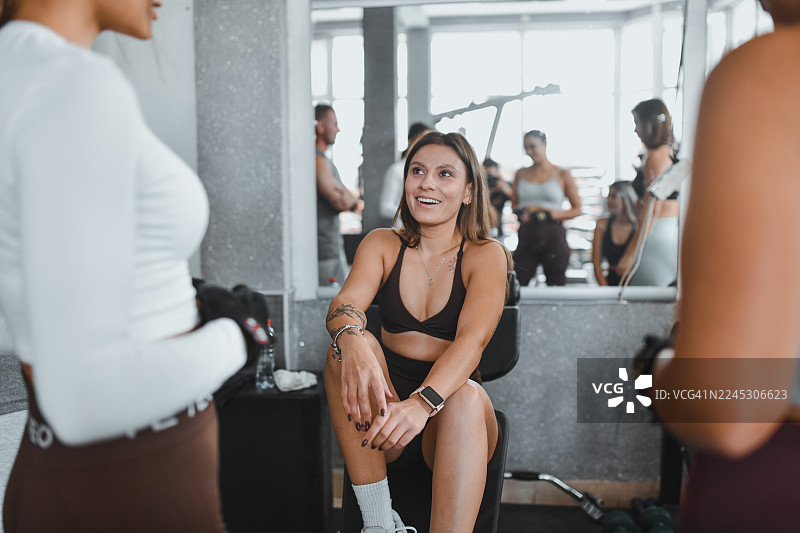 精疲力尽的女运动员在健身房与一群女性一同剧烈训练后坐下休息图片素材