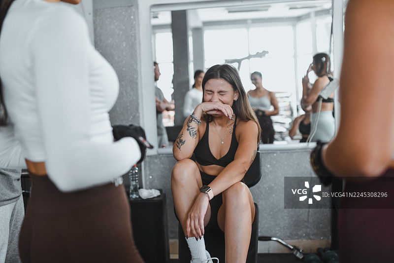 精疲力尽的女运动员在健身房与一群女性一起剧烈训练后坐下图片素材