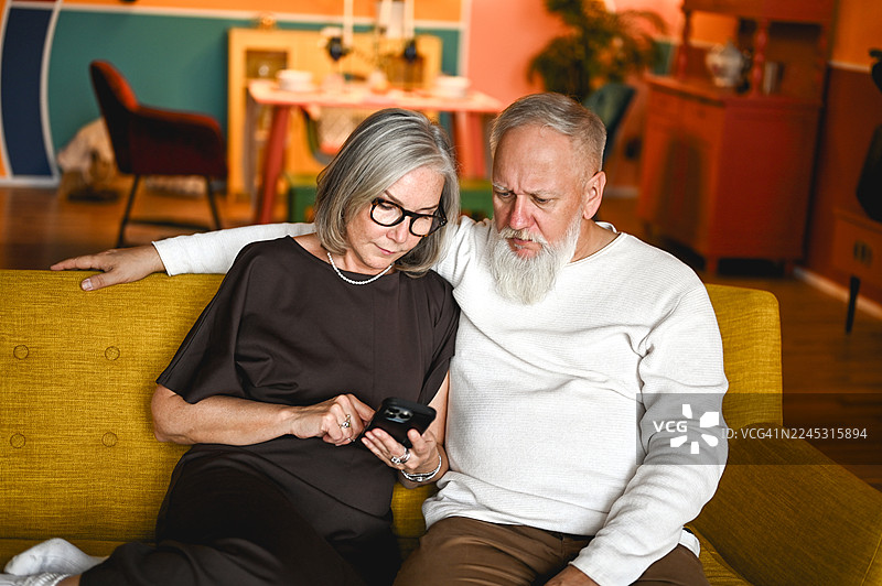 年迈夫妇在沙发上学习使用智能手机图片素材