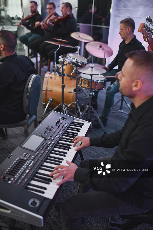 键盘手在鼓、小提琴手和乐队的伴奏下进行现场录音室表演图片素材