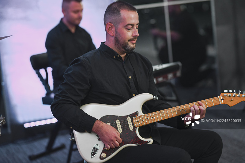 身着黑衣的吉他手在现场录音室弹奏白色电吉他图片素材
