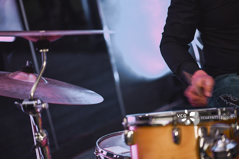 鼓手在夜晚的舞台上进行现场表演，敲击着架子鼓和钹图片素材