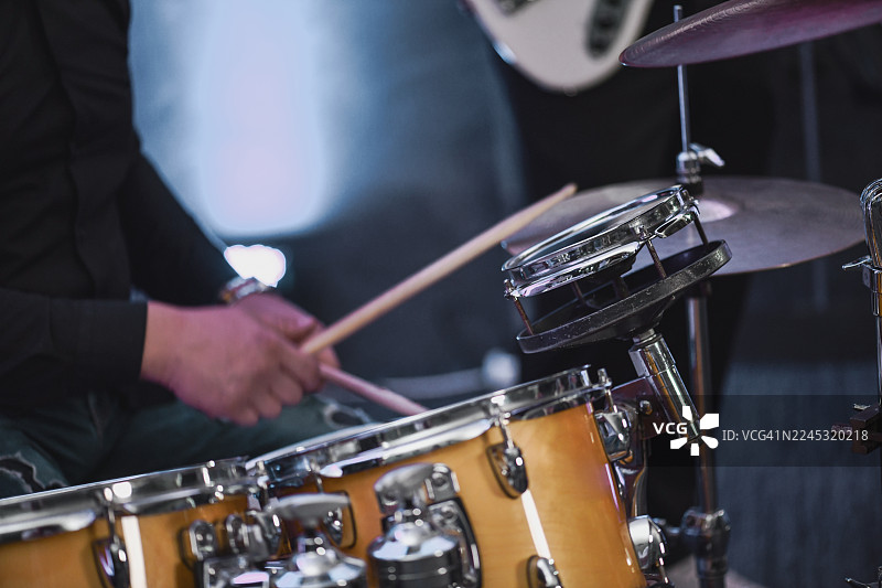 鼓手在夜晚的舞台上进行现场表演，敲击着装有镲片的架子鼓图片素材