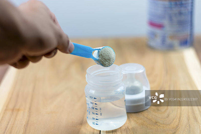 浅色背景下特写奶粉和蓝色勺子。罐子里的婴儿奶粉和量勺。婴儿用奶粉和勺子。婴儿奶粉和奶瓶图片素材