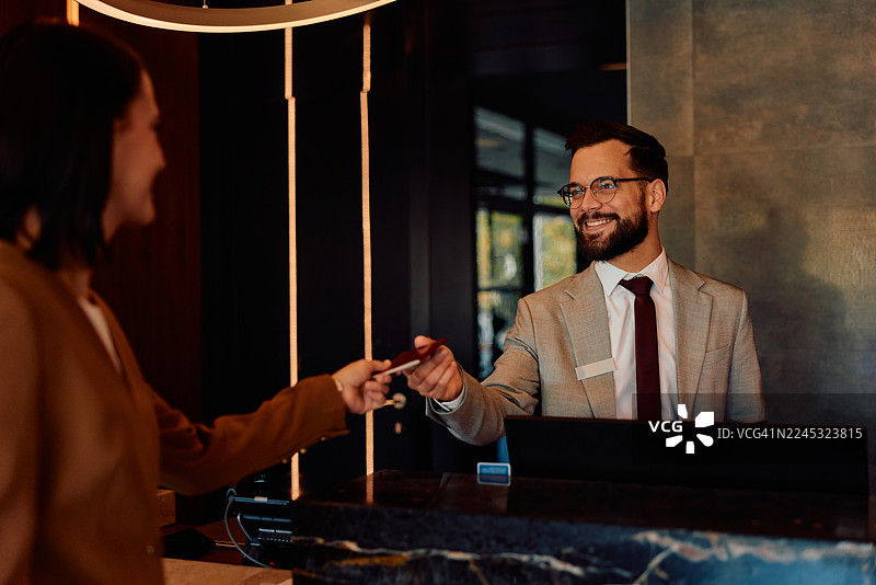男士在酒店前台将房卡交给女士图片素材
