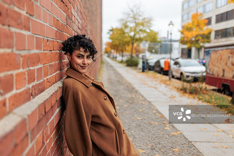 自信的女性站在砖墙前图片素材
