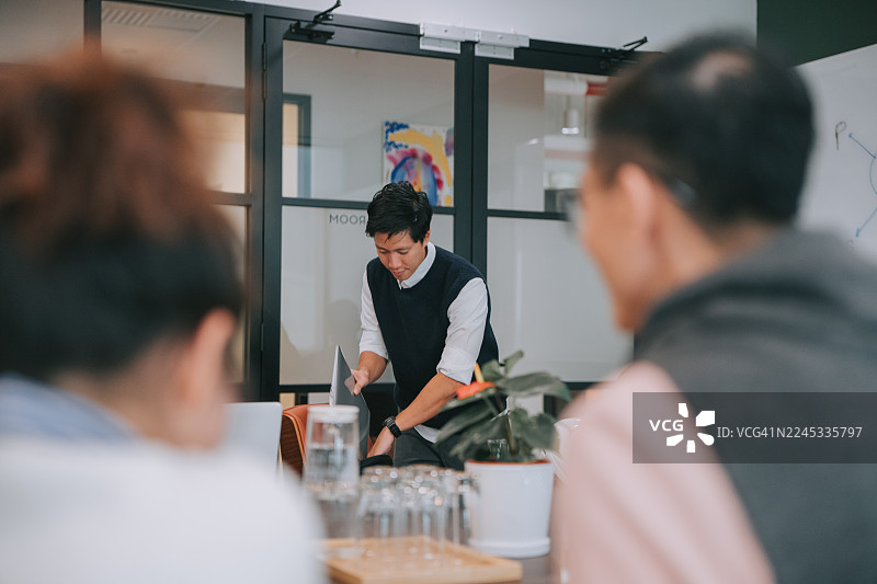 中国办公室职员抵达，并从会议桌上的笔记本电脑包中取出笔记本电脑图片素材