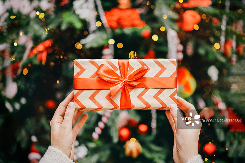 温柔的女性双手将礼品盒放在圣诞树下图片素材