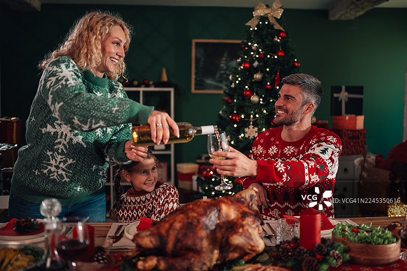 一家人庆祝圣诞节，在餐桌旁倒酒图片素材