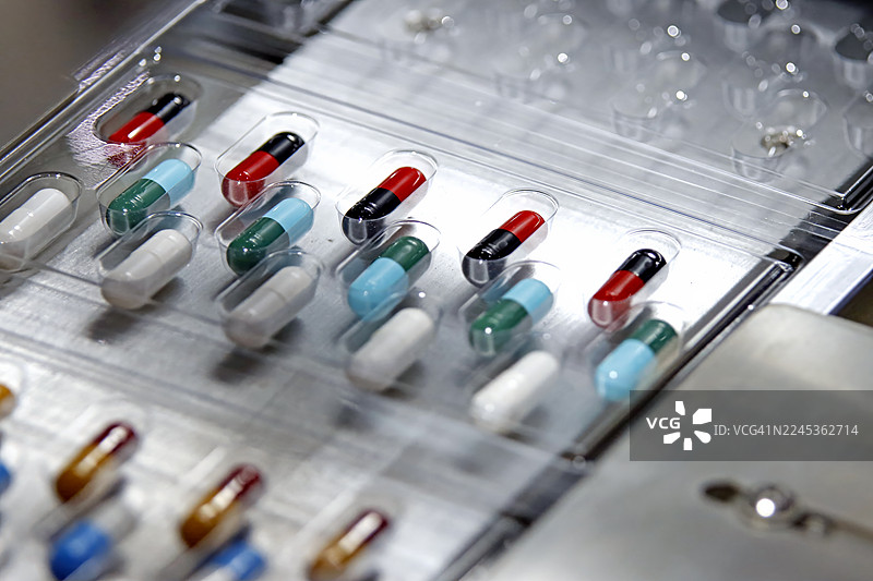 自动化泡罩包装机将多色药用胶囊插入透明塑料托盘图片素材