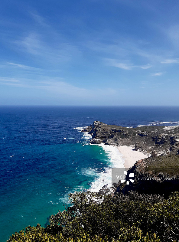 清澈湛蓝的天空下，原始的白色沙滩与绿松石般的海水交汇，远处是崎岖的悬崖和茂密的绿色植被，令人惊叹的航拍景象。图片素材