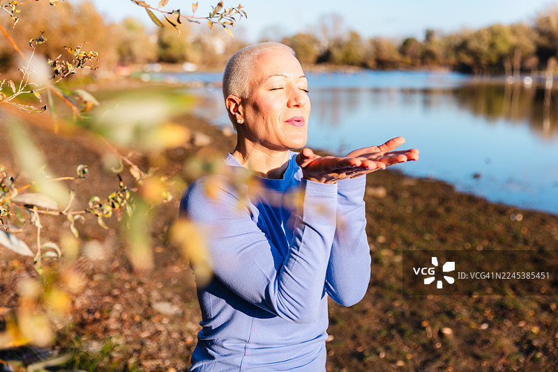 秋日阳光下，女子在湖边冥想，呼吸着宁静、平和的幸福感图片素材