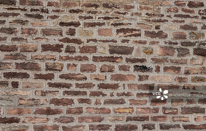 质朴而富有纹理的砖墙全景，呈现出各种棕色和灰色调，非常适合用作背景或建筑元素。图片素材
