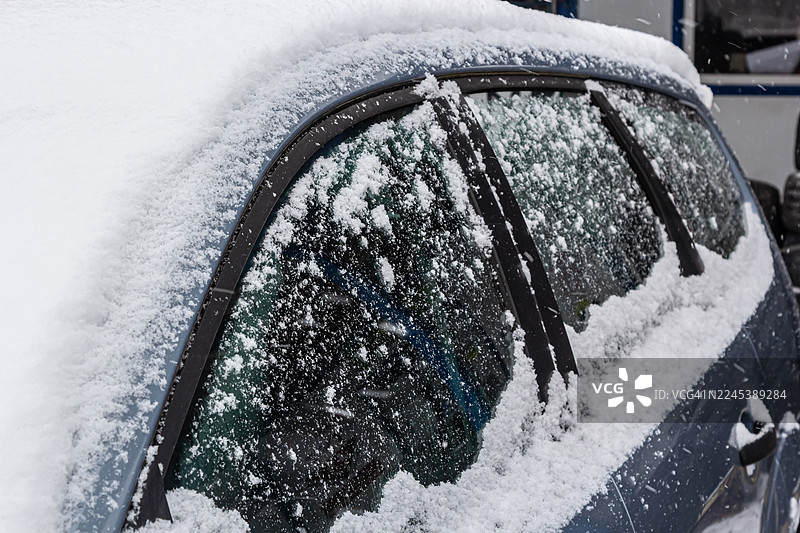 特写镜头：一辆被雪覆盖的汽车，突显冬季天气和严峻的驾驶条件图片素材