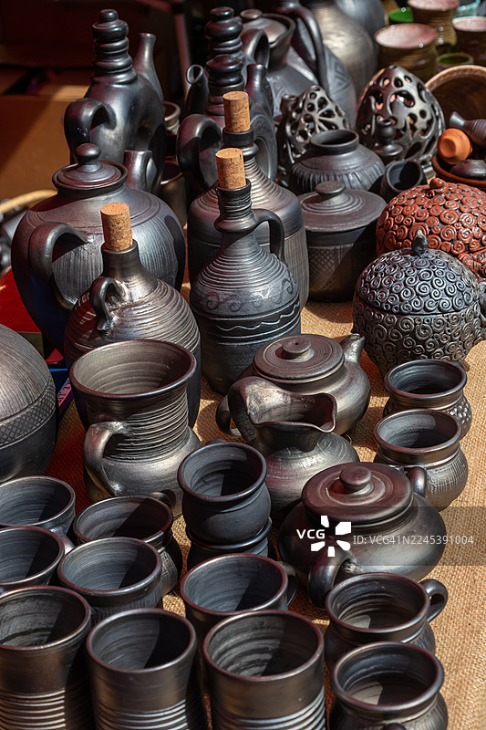 市场摊位上各种传统手工陶罐和陶瓷的高角度视图，展示了精湛的工艺和文化遗产图片素材