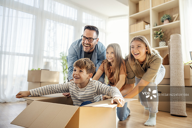 搬家日，一家人在新家玩纸箱图片素材