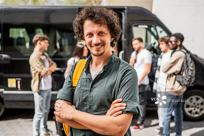 微笑的男士带领学生团体乘坐巴士出游图片素材