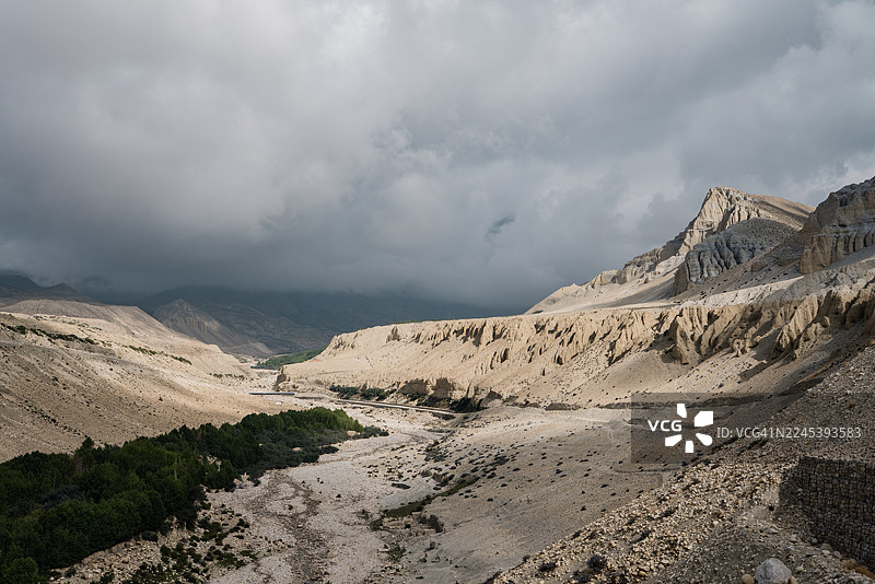 尼泊尔，马斯塘，干涸河床和头顶乌云笼罩下的戏剧性山景图片素材