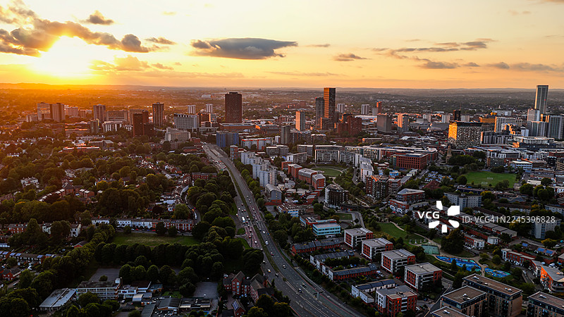 伯明翰城市天际线的日落鸟瞰图，包含现代摩天大楼和历史建筑，城市景观和交通道路沐浴在晚霞中，城市设计的旅行与商业理念图片素材