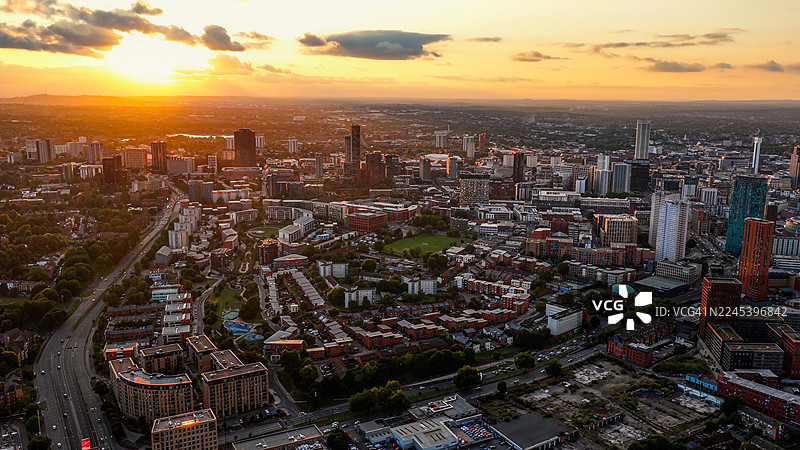日落时分伯明翰市天际线的鸟瞰图，展示了现代摩天大楼和历史建筑，城市景观和交通道路在晚霞中，城市设计的旅行和商业理念图片素材