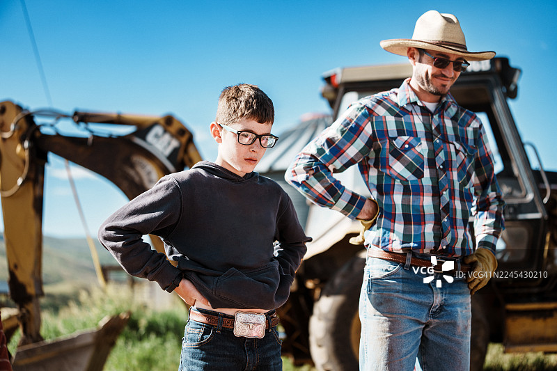 父亲和儿子在家庭牧场的挖掘机旁图片素材