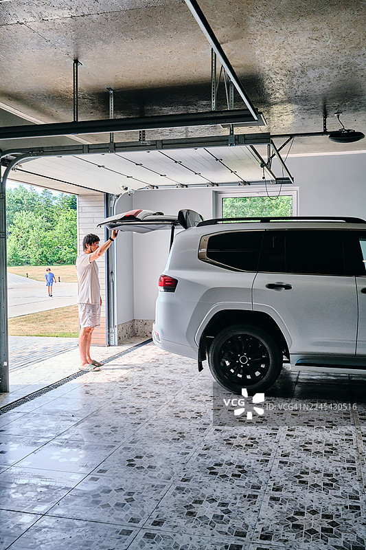 男人在现代家居车库里装载SUV后备箱图片素材