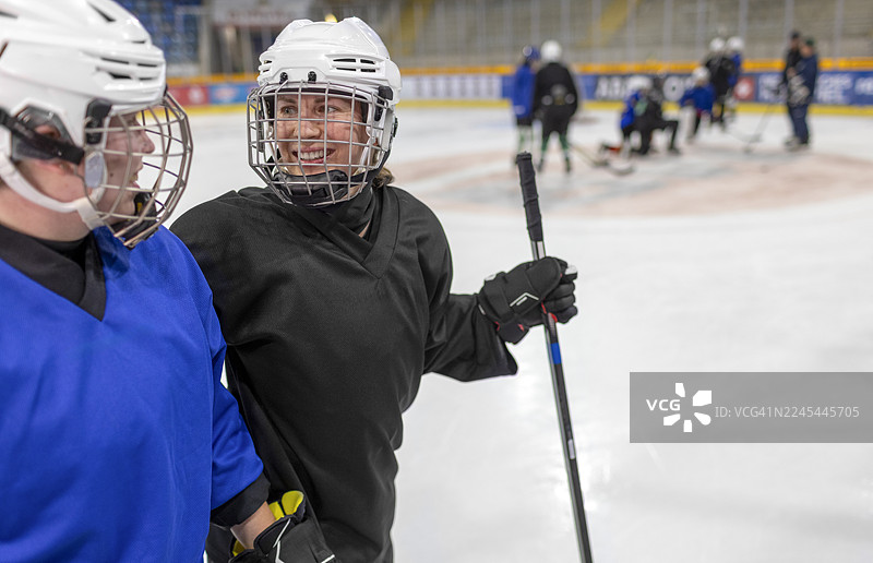 两位微笑的女子冰球运动员在冰场上交谈图片素材