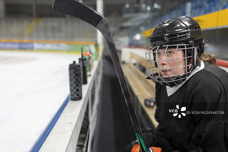 冰球女运动员坐在冰场的替补席上图片素材