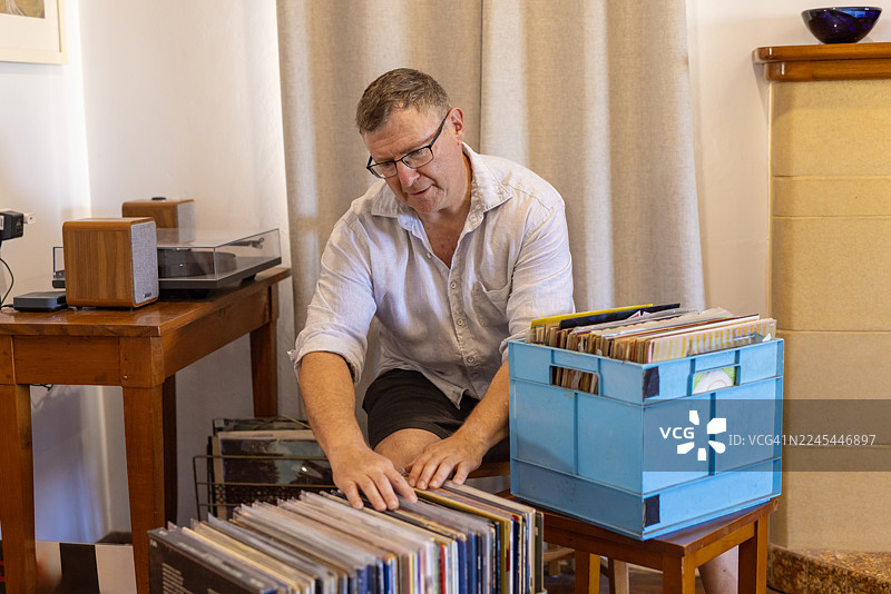 中年男子正在欣赏他的黑胶唱片收藏图片素材
