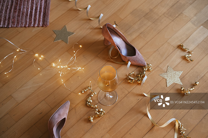 派对或after party背景生日、婚礼、圣诞节、新年，优雅的高跟鞋放在木地板上，周围环绕着节日装饰和一个酒杯图片素材