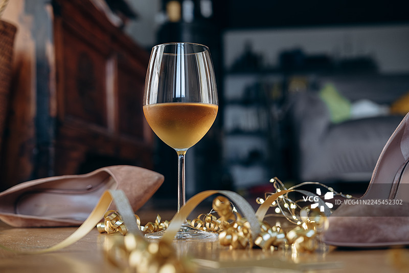 时尚鞋子和装饰品旁边放着一杯白葡萄酒，营造出欢乐喜庆的庆祝场景图片素材