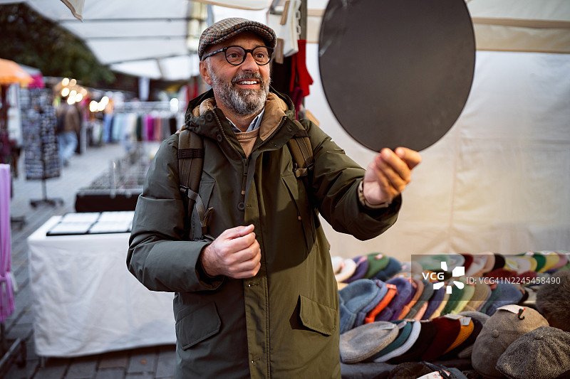 秋天，一位中年男子在柏林一家名为Hackescher Markt的商店里，在镜子前试戴宽檐帽图片素材