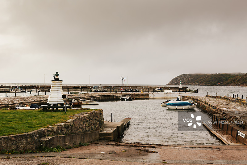 雨天，海边渔村，港口有船只和航标。图片素材