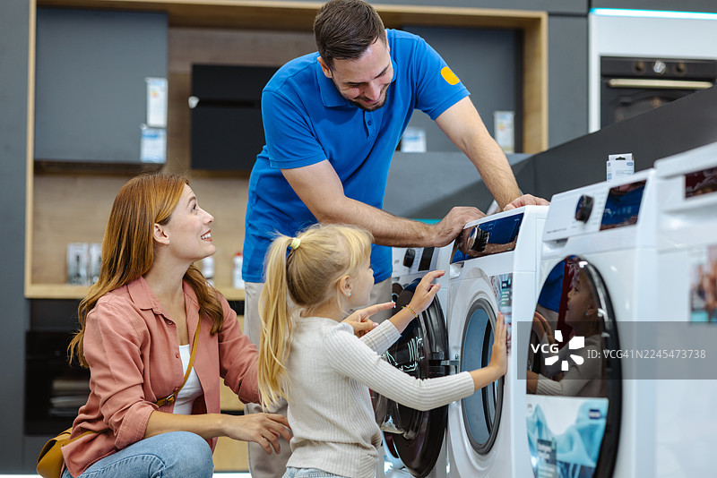 一家人在电器商店里，在友好的销售人员的陪同下，选购一台新的洗衣机。图片素材