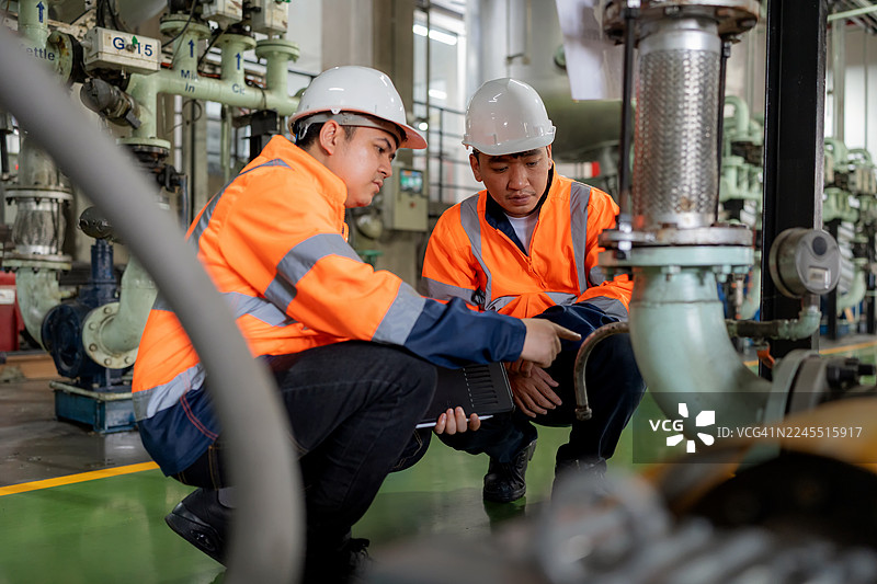维护工程师在石化厂使用数字平板电脑检查泵和阀门的运行情况。他们通过现代工业技术监测性能，以提高石油行业的润滑效率、安全性和可持续性。图片素材