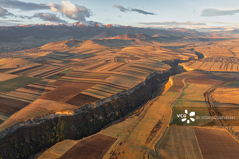 日出后，亚美尼亚洛里省的农田和村庄的鸟瞰图——带有山脉背景的几何形状农田。图片素材