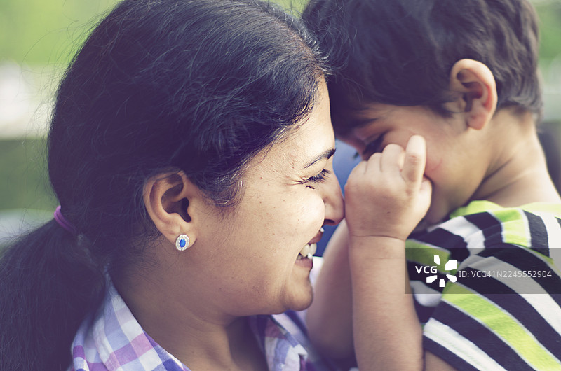 印度母亲拥抱幼儿儿子的户外肖像。 这张温馨的图片捕捉了家庭亲情和母爱的美好瞬间，非常适合儿童、育儿、幸福和春季等主题。图片素材