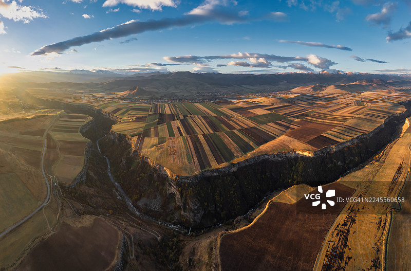 亚美尼亚洛里省的农田和村庄的鸟瞰图——日出后光线下带有山脉背景的几何农田。图片素材