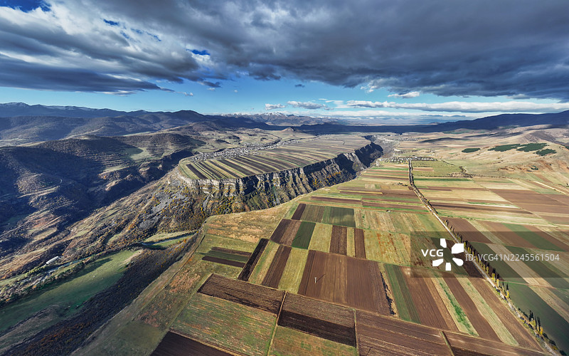 亚美尼亚洛里省深层地质裂谷和图案化农田的鸟瞰图，背景是晴朗白昼下的山脉。图片素材