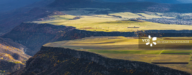 从空中俯瞰亚美尼亚洛里省附近的农田和山脊，光影和云层投下的阴影戏剧般地笼罩着大地。图片素材