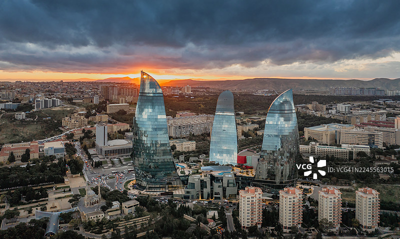 日落时分阿塞拜疆巴库火焰塔的鸟瞰图，展示了城市天际线和在戏剧性晚霞映衬下闪耀的城市灯光。图片素材