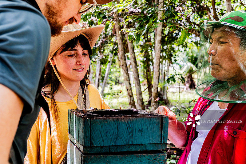 游客与当地男子在热带雨林中了解养蜂知识图片素材